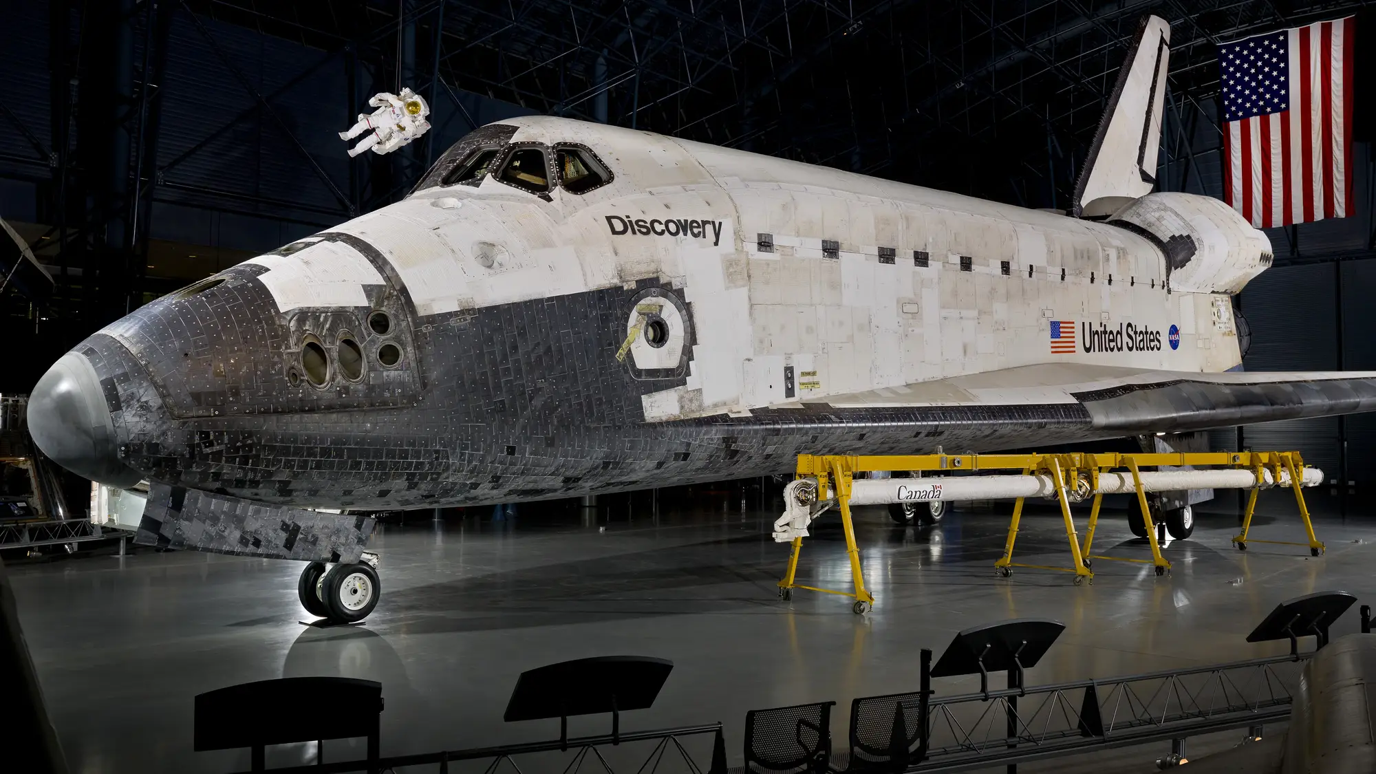 Space Shuttle Discovery on display in the Smithsonian's Udvar-Hazy Center, seen side-on behind a visitor railing.